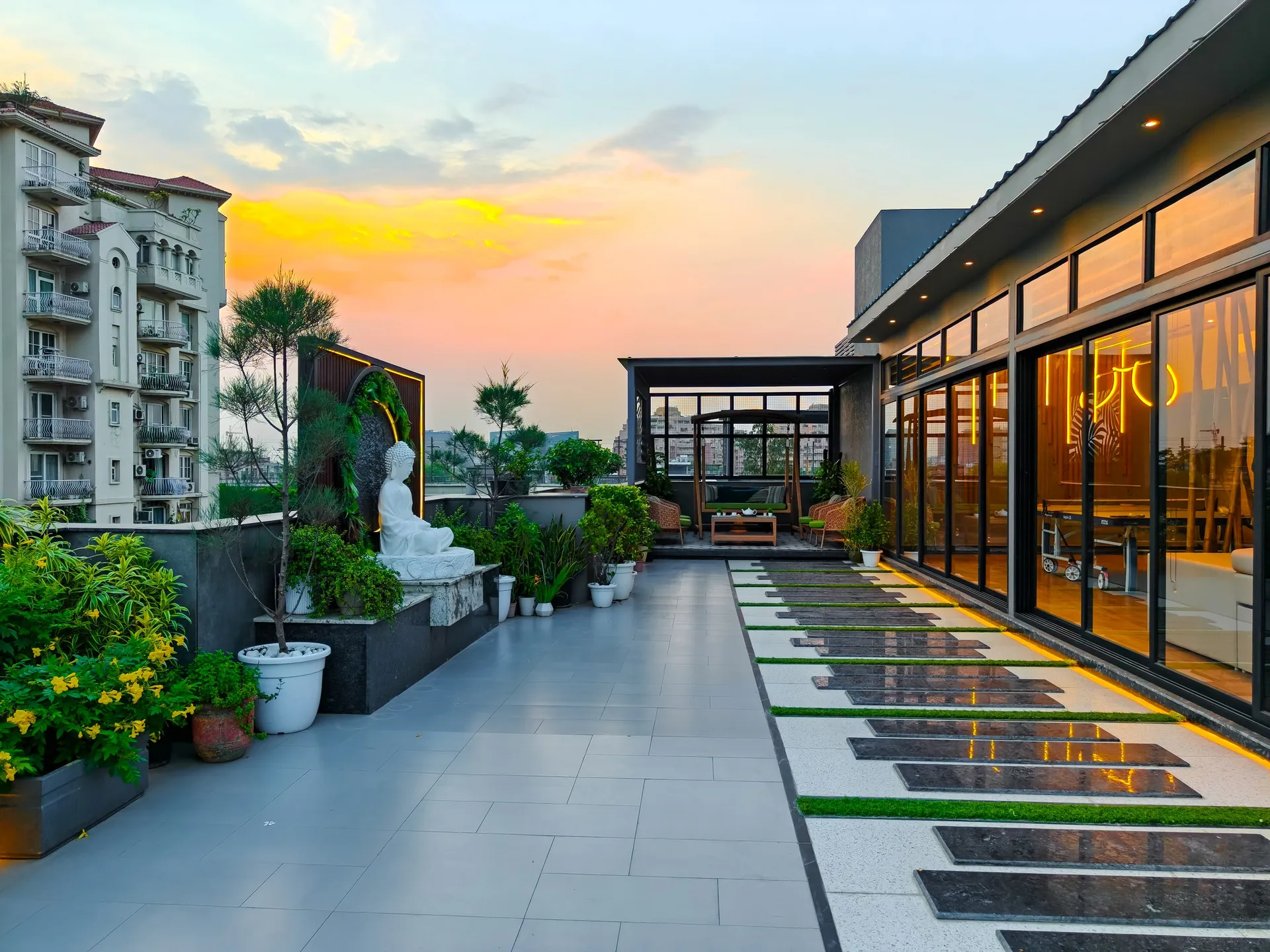 Rooftop terrace at sunset with planting and a glass pavilion, built by LifeWall