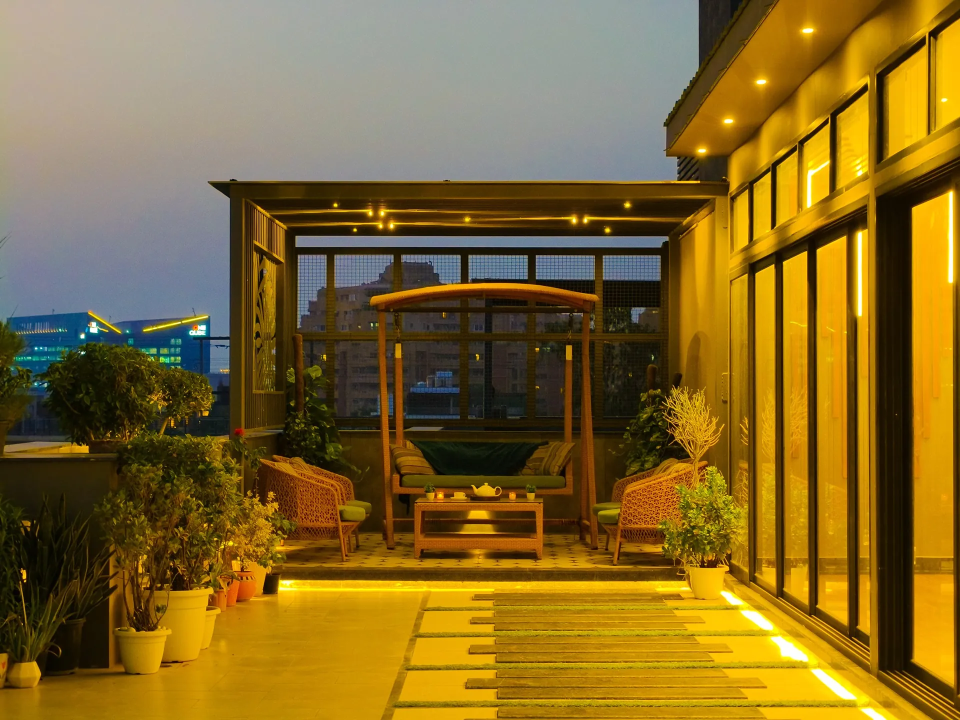 Pergola lounge with swing seating, lit at dusk, on a LifeWall terrace